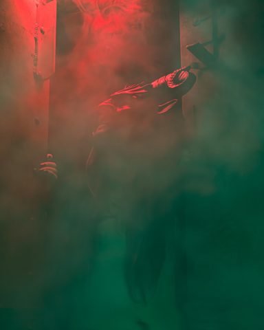 Dunkle Silhouette einer Person vor einem nebulösen, rot-grünen Hintergrund.